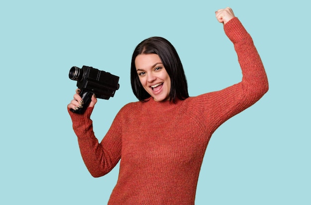 Photo a young woman happily films with an antique video camera on an isolated background