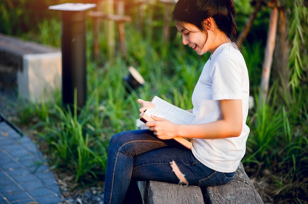 自然の中で本を楽しく読んでいる若い女性