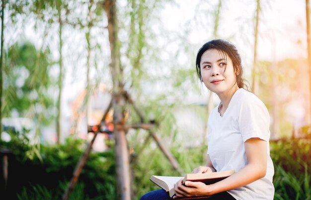 Young woman happily reading the book in nature