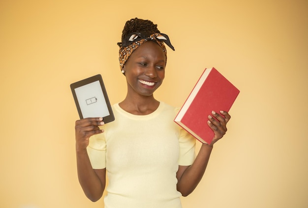 молодая женщина довольна своей печатной книгой, держа в руках электронную книгу с разряженным аккумулятором.
