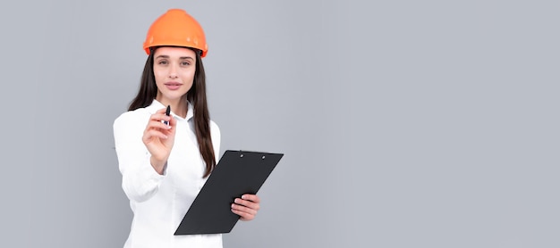 Young woman in hard hat helmet with clipboard isolated on grey background Architect woman wear