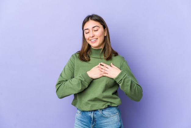 Young woman has friendly expression, pressing palm to chest