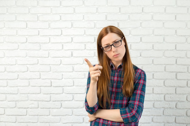 Young woman has idea, pointing with finger up