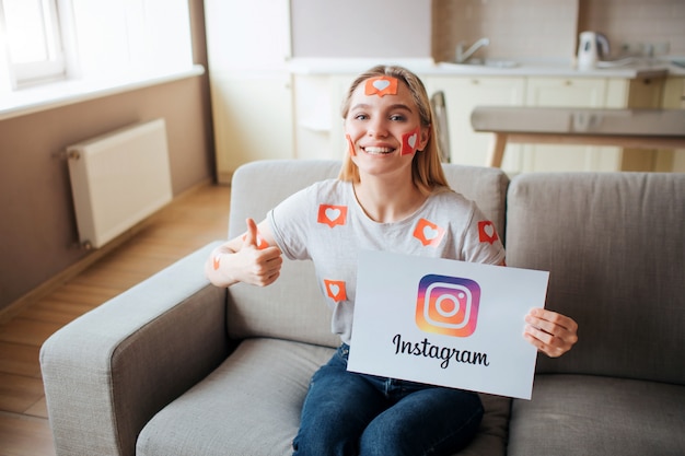 Young woman has social media addiction. addictiveness from smartphones. young woman sit on sofa in living room and smile. like symbol. happy positive woman.