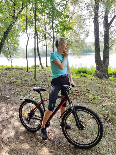 若い女性が公園で自転車で止まり電話で話しています観光とスポーツ