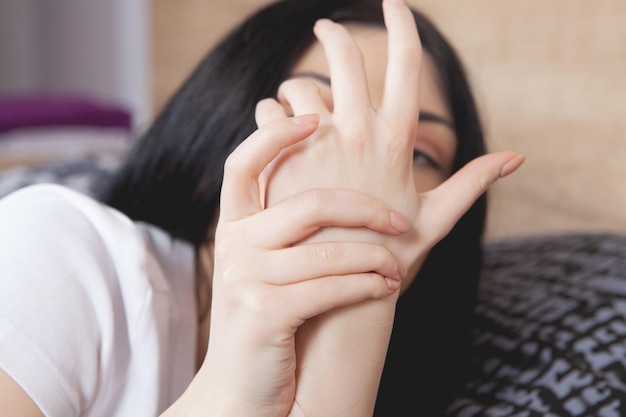 사진 젊은 여자는 회색 배경에 손목 통증이 있습니다