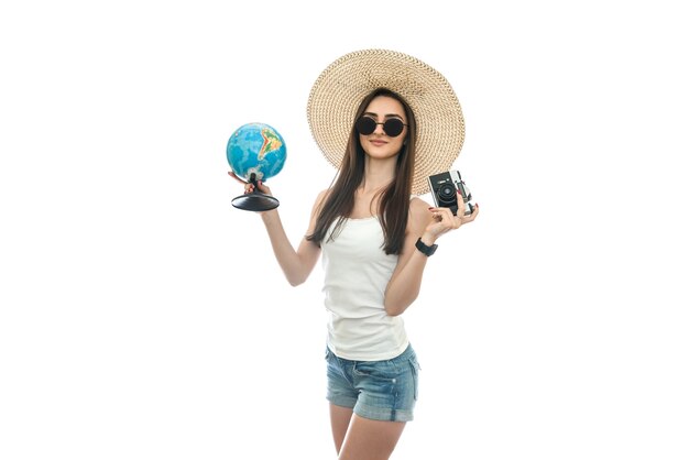 Young woman in hat holding globe and camera