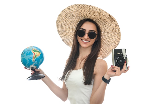 地球儀とカメラを保持している帽子の若い女性