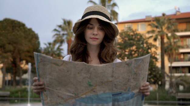 Foto giovane donna in cappello che tiene guardando una mappa della città del sud in francia