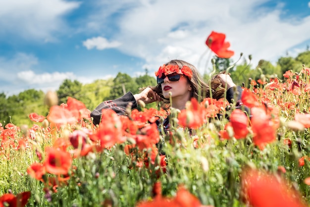 Young woman in hat walk at poppy field pick flowers. summer time