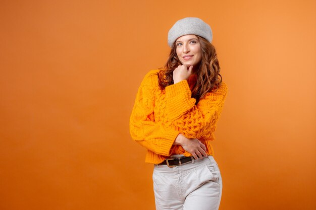 young woman in a hat on a yellow background and a sweater