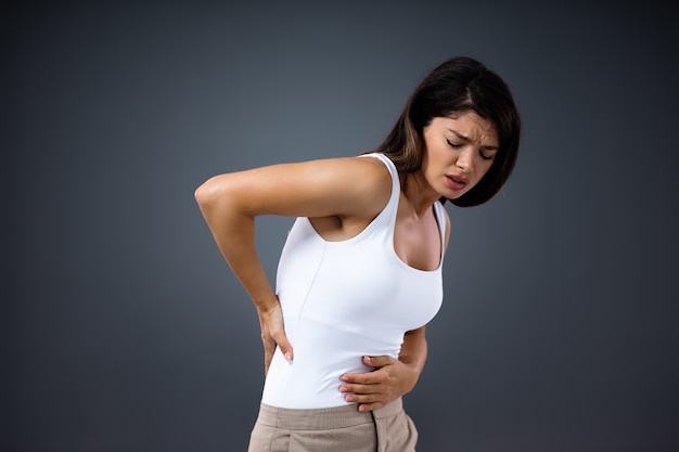 Young woman having back pain and holding her backs.