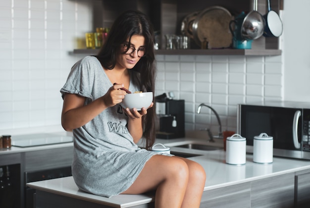 Photo young woman having breakfast in the kitchen