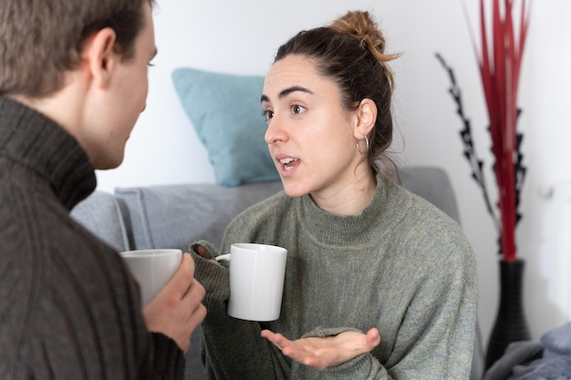 Young woman having conversation with friend and holding a cup of coffee