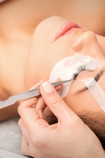 Young woman having eyelash extension procedure