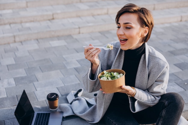 Young woman having lunch and working online