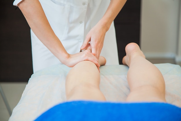 Young woman having massage at beauty spa salon Beautician massaging female legs Bodycare concept