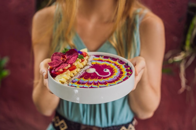 Young woman having a mediterranean breakfast eats healthy tropical breakfast smoothie bowl with