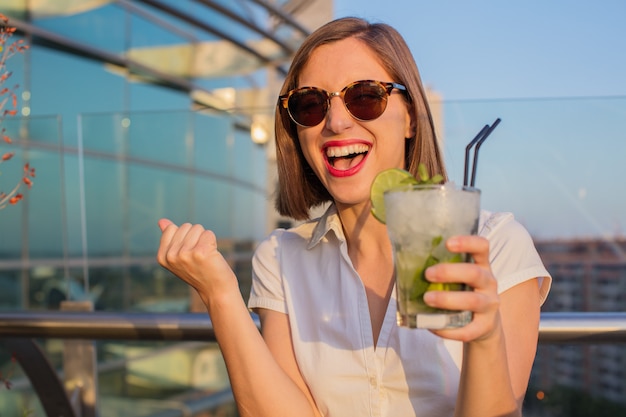 young woman having a mojito in a rooftop.