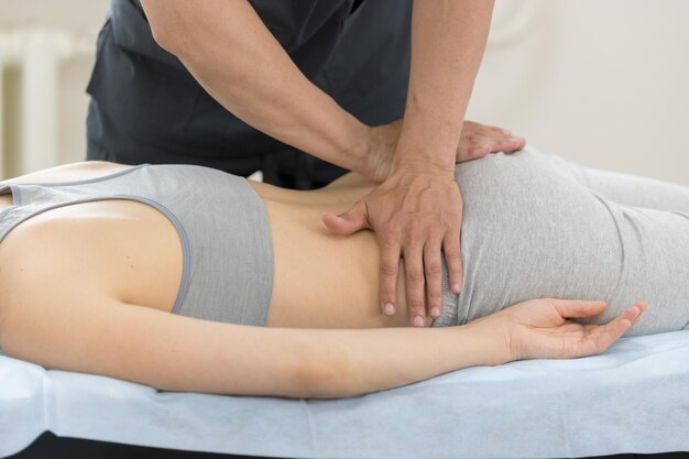 Photo young woman having osteopathy treatment  pushing on the loin and butt