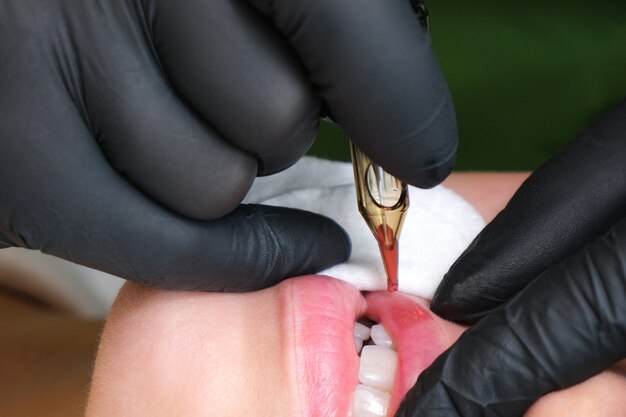 Young woman having permanent makeup on her lips at the beauticians salon.