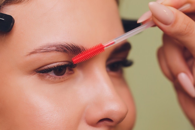 Young woman having professional eyebrow correction procedure in beauty salon.