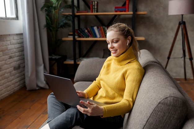 Young woman having video call on laptop computer at home. High quality photo