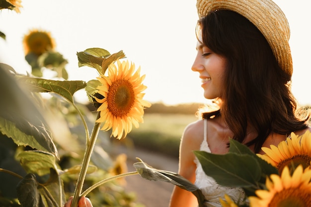 Young woman having a walk in sunflowers field in the morning