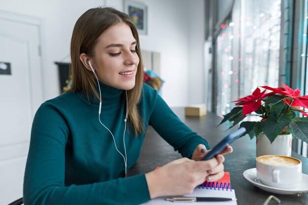 Молодая женщина в наушниках, используя смартфон для работы и учебы