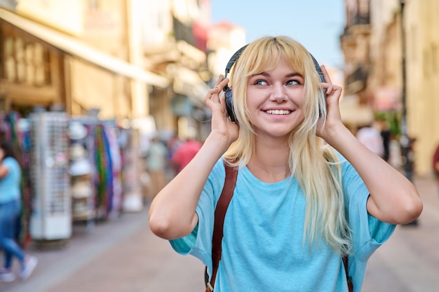 Young woman in headphones with backpack on street of tourist city