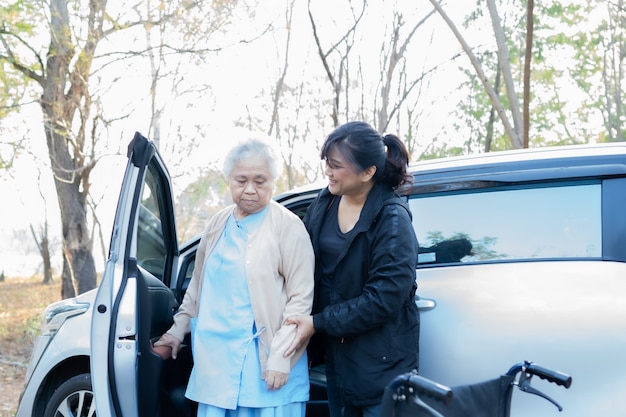 車椅子の上級の患者を助ける若い女性