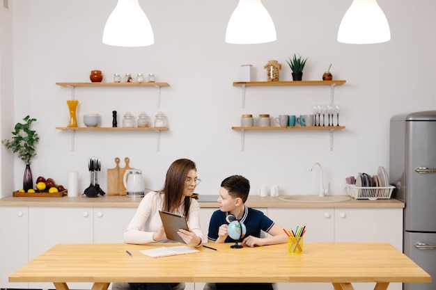 a young woman helps a boy with his lessons using a tablet and a globe a homeschooling student does his homework with the help of a tutor