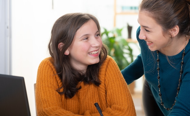 Photo young woman helps a teen girl with  homework