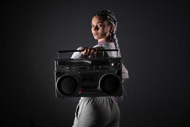 Young woman on her back holding retro tape recorder while looking at camera