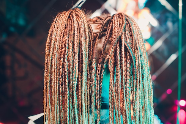 A young woman, her hair braided in pigtails thin blue.