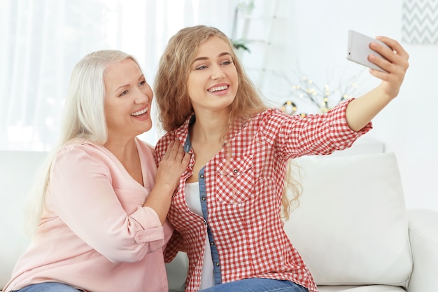 Giovane donna e sua madre che prendono selfie a casa