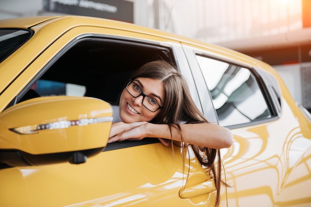 Young woman in her new car smiling