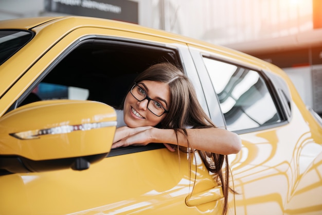 彼女の新しい車を笑顔で若い女性