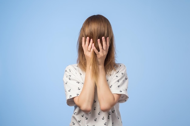 Young woman hides her face with hair and hands