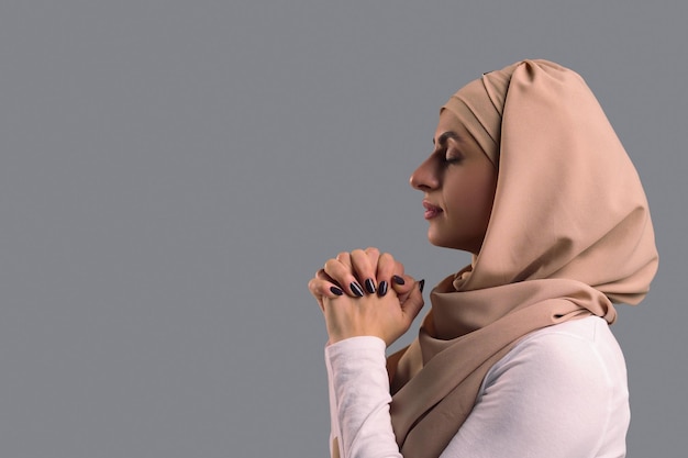 Foto giovane donna in hijab che prega con gli occhi chiusi