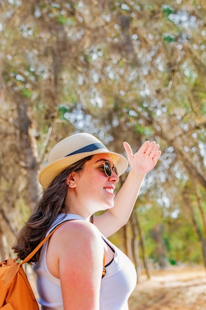 Young woman hiker stands in the forest and look far away at sunny day