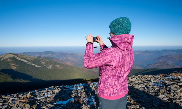 彼女のスマートフォンで写真を撮る若い女性ハイカー