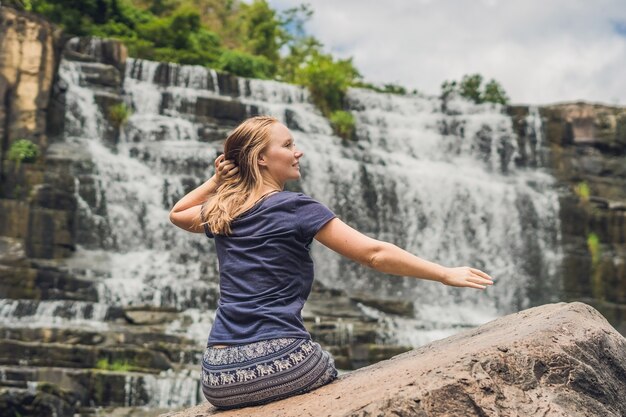 Young woman hiker tourist on the background of amazing pongour waterfall