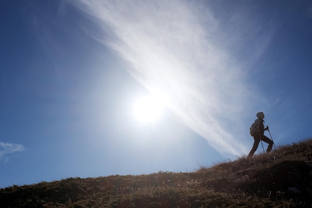 Viandante della giovane donna con uno zaino sulla cima della montagna