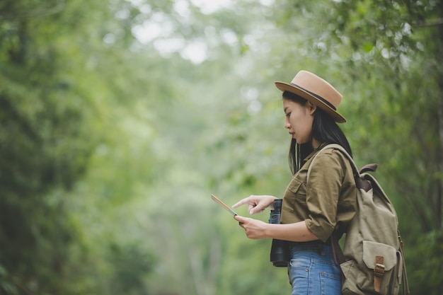 Young woman hiker with backpack watching trekking map, Hiking concept.