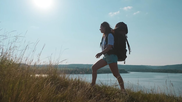 The young woman hiking with backpack along the beautiful coast