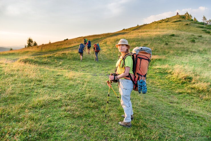Young woman hiking with friends in the sunset mountains
