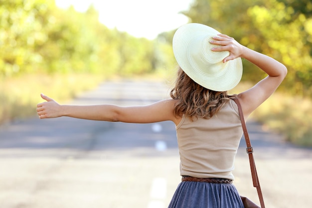 道路でヒッチハイクする若い女性