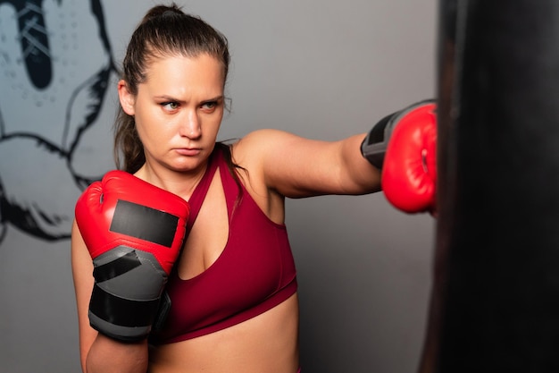 A young woman hits a punching bag in the gym Sports life