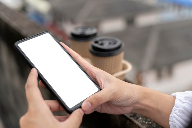 Young woman hold smartphone with white screen while sitting on a couch Outdoors woman using a phone in the city